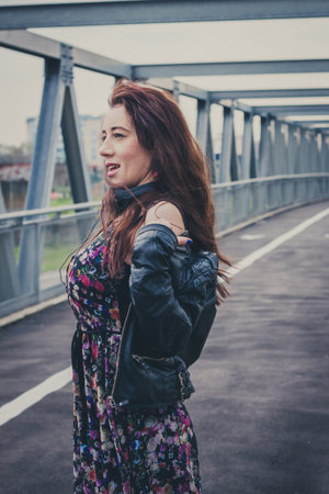 Pretty girl with black leather jacket posing on a bridge