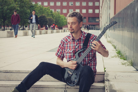 Man in short sleeve shirt playing electric guitar in the street