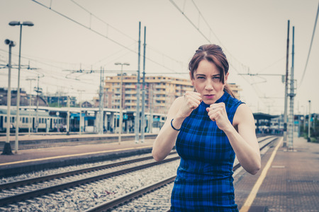 Pretty girl ready to fight along the tracks in a railroad stationの写真素材