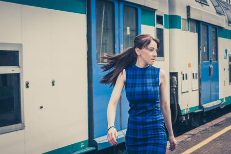 Pretty girl walking along the tracks in a railroad stationの写真素材