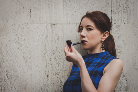 Pretty girl smoking vintage pipe in the streetの写真素材