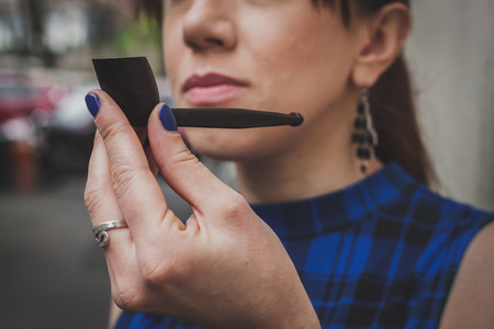 Detail of a pretty girl smoking vintage pipe in the streetの写真素材