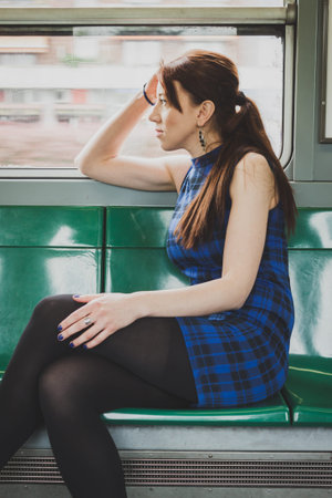 Pensive pretty girl sitting inside subway train