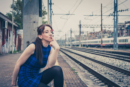 Pretty girl posing along the tracks in a railroad stationの写真素材