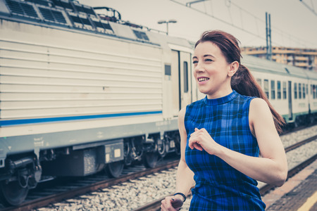 Pretty girl running along the tracks in a railroad stationの写真素材