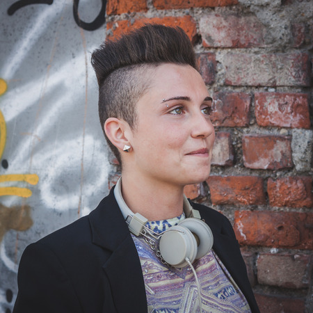 Pretty short hair girl with black jacket posing against a wallの写真素材
