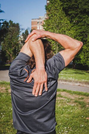 Mature long haired athlete stretching in a city parkの写真素材