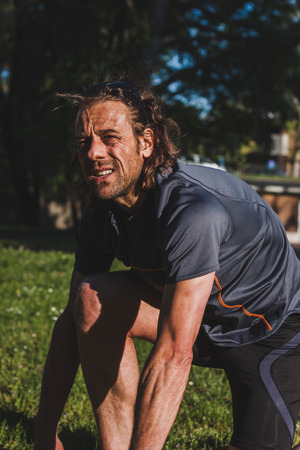 Mature long haired athlete stretching in a city parkの写真素材