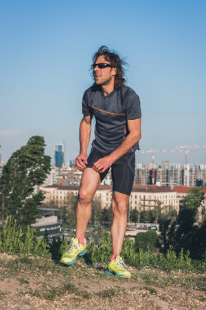 Portrait of a mature long haired athlete posing in a city park