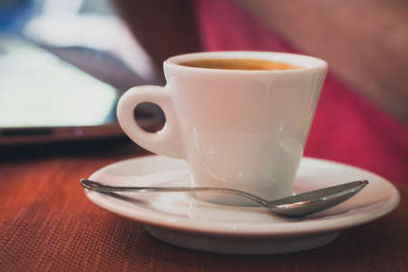 Cup of coffee with spoon on a tableの写真素材