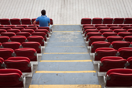 Empty red stadium seats with a man aloneの写真素材