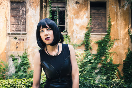Pretty dark goth girl posing in a city park