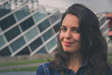 Pretty girl with long hair poses in the city streetsの写真素材