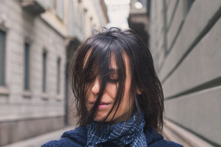 Beautiful girl with long hair posing in the city streetsの写真素材