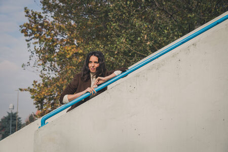 Beautiful young woman with long hair posing in a city parkの写真素材