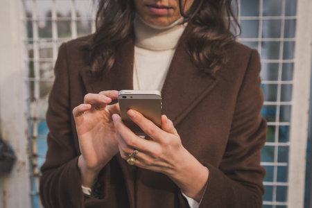 Detail of a beautiful young woman with long hair textingの写真素材