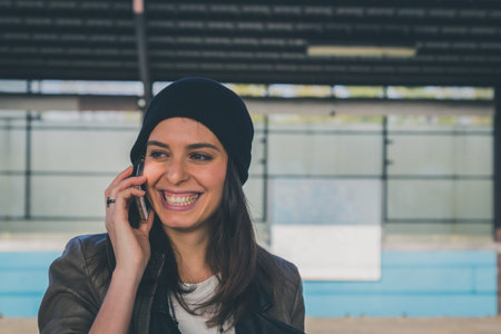 Pretty girl with beanie talking on phone in a metro station