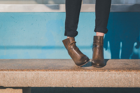 Detail of ankle boots on bench in a metro stationの写真素材
