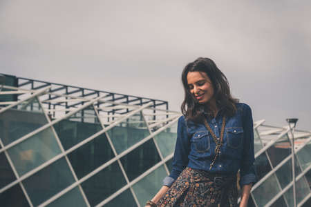 Pretty girl with long hair poses in the city streetsの写真素材