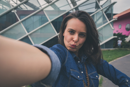 Pretty girl with long hair takes a selfie in the city streetsの写真素材