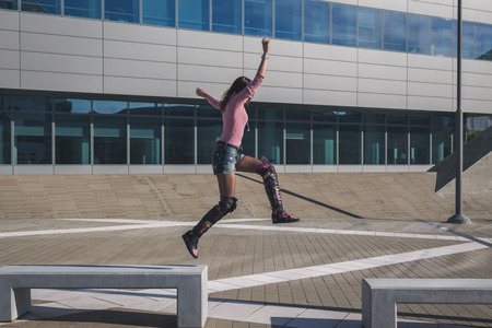 Beautiful young brunette with over the knee boots jumping in the city streetsの写真素材