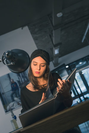 Beautiful young brunette with turban reading book in an office