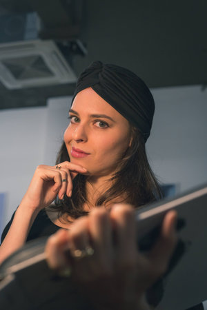 Beautiful young brunette with turban reading book in an office