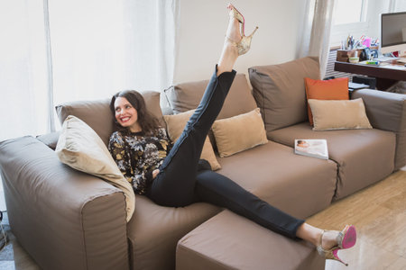 Beautiful young brunette with long hair relaxing on a couch