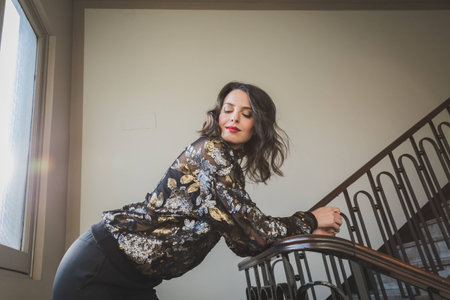 Portrait of a beautiful young brunette with long hair posing on the stairsの写真素材