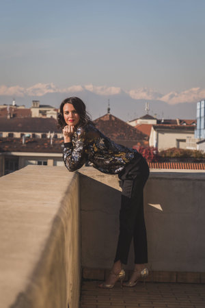 Portrait of a beautiful young brunette with long hair posing on a balconyの写真素材