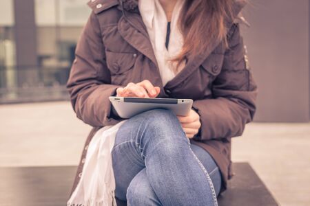 Detail of a young woman working with her tablet in the city streetsの写真素材