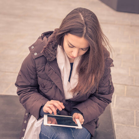 Young beautiful girl working with her tablet in the city streetsの写真素材