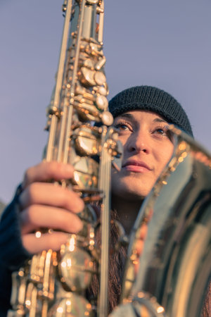 Beautiful young woman posing in the city streets with her saxophoneの写真素材