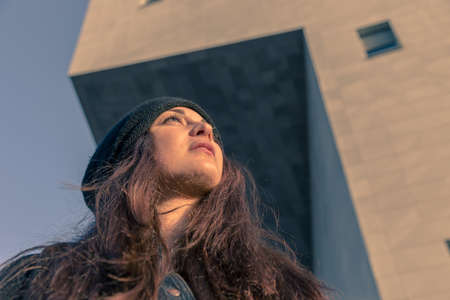 Beautiful young woman with long hair posing in the city streetsの写真素材