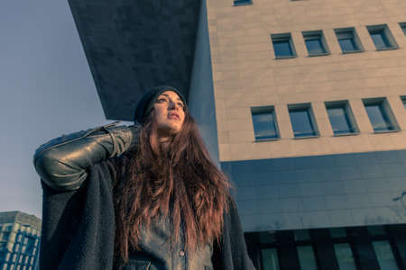 Beautiful young woman with long hair posing in the city streetsの写真素材