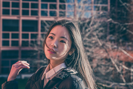 Young beautiful Chinese girl with long hair posing in the city streets