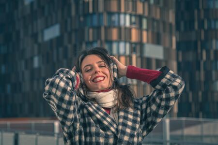 Beautiful young brunette with long hair posing in the city streetsの写真素材