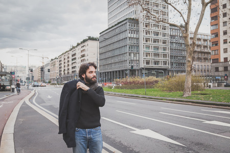Young handsome bearded man with coat posing in the city streetsの写真素材