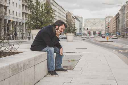 Young handsome bearded man with coat posing in the city streetsの写真素材