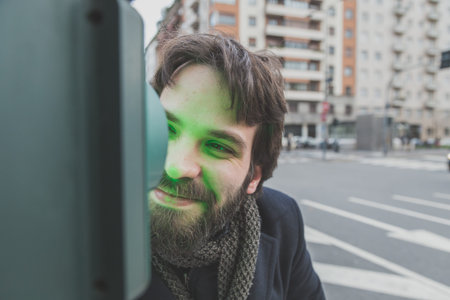 Young handsome bearded man with coat posing in the city streets