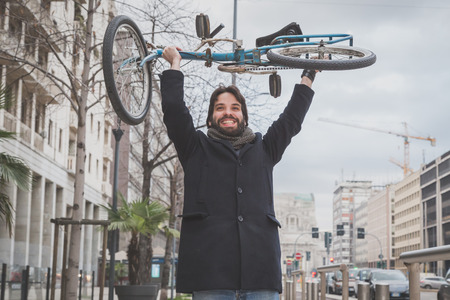 Young handsome bearded man posing with his bicycle in the city streetsの写真素材