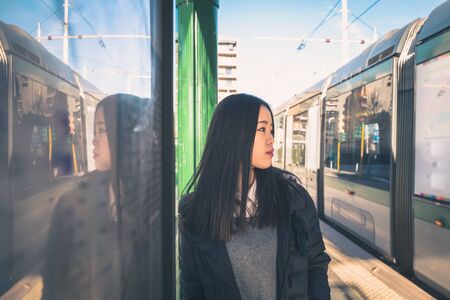 Young beautiful Chinese girl with long hair posing in the city streetsの写真素材