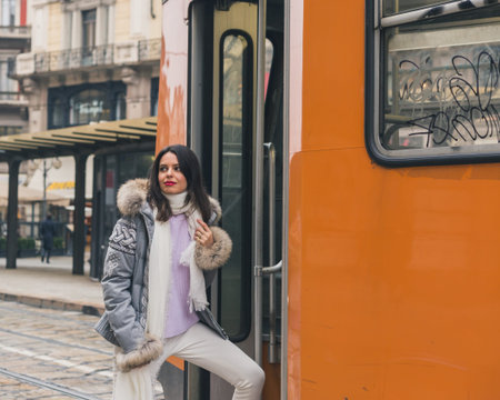Beautiful young brunette with long hair taking a tramの写真素材
