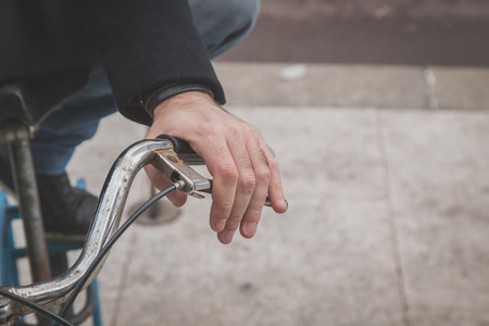 Detail of a young man posing with his bicycle in the city streetsの写真素材