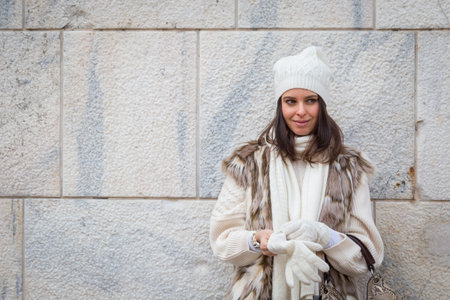 Beautiful young woman wearing ecological fur poses in the city streetsの写真素材