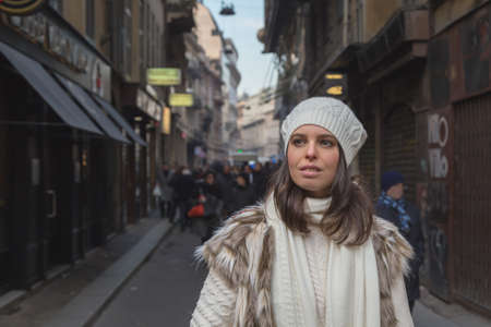 Beautiful young woman wearing ecological fur poses in the city streetsの写真素材