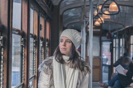 Beautiful young woman wearing ecological fur poses on a tramの写真素材