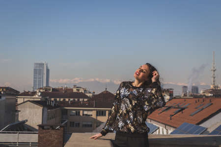 Portrait of a beautiful young brunette with long hair posing on a balconyの写真素材