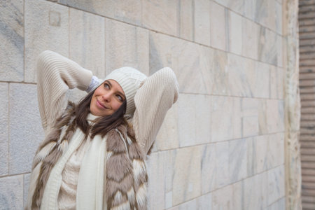 Beautiful young woman wearing ecological fur poses in the city streetsの写真素材