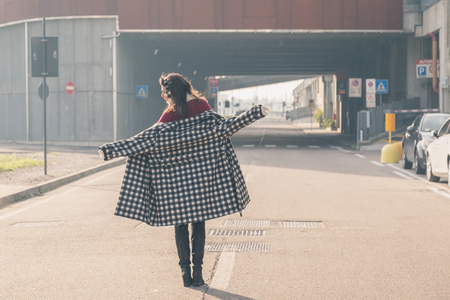 Beautiful young brunette with long hair posing in the city streetsの写真素材